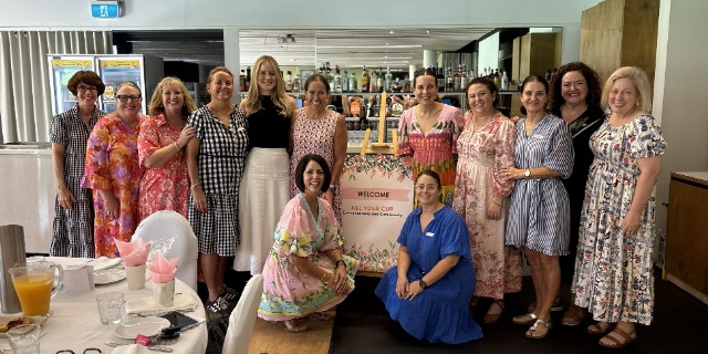 Group of staff and community members gathered indoors for a welcome event photo.