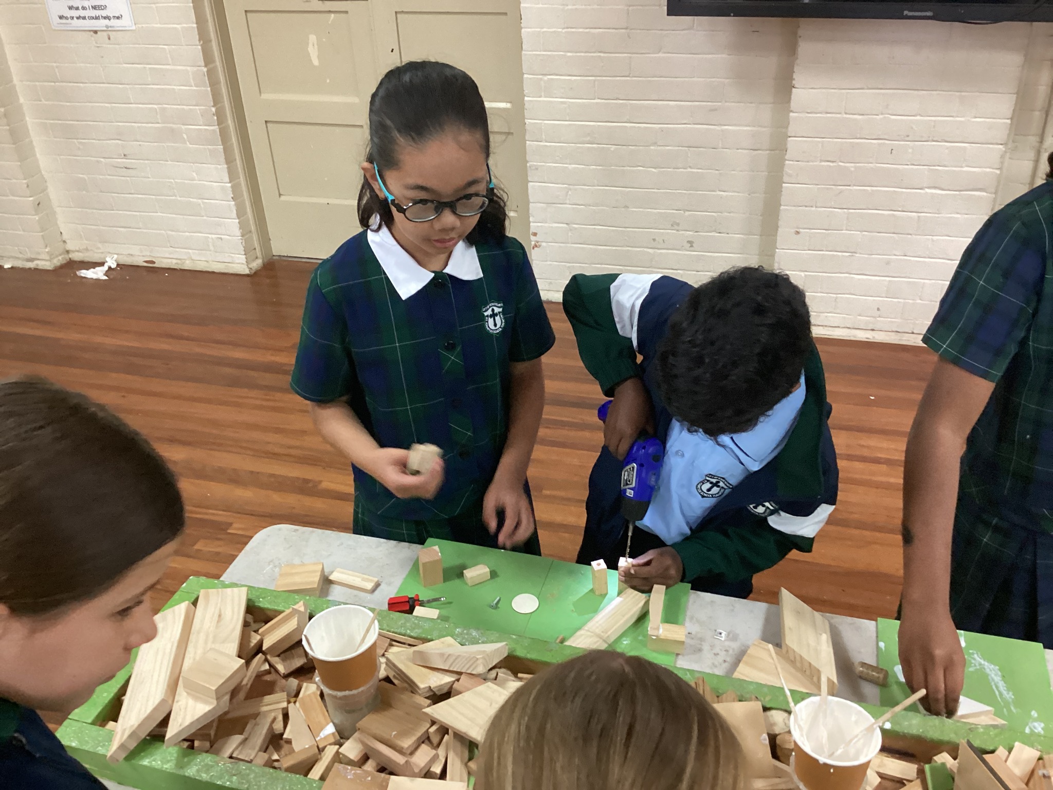 Students collaborating on a hands‑on construction activity using wooden pieces at a classroom table.